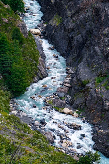 Río de montaña entre rocas y árboles.