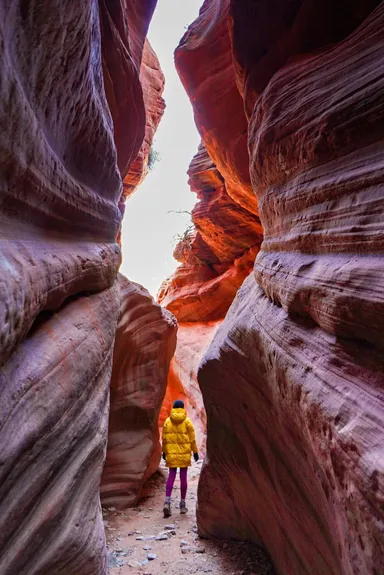 Person in yellow coat walking through narrow canyon.