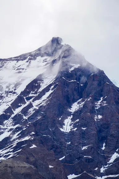Pico de montaña nevado con niebla.
