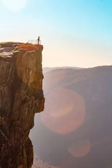 Persona celebrando en un mirador en un acantilado.